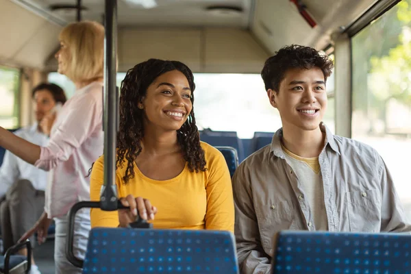 Neşeli Asyalı adam ve siyah kadın birlikte otobüse biniyor.