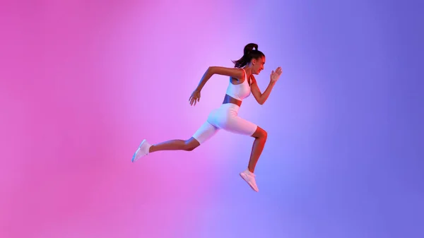 Fit Bayan Neon Arkaplanı Üzerinde Orta-Hava Egzersizinde Atlıyor — Stok fotoğraf