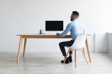 Arap adam boş bilgisayar monitörüne bakıyor