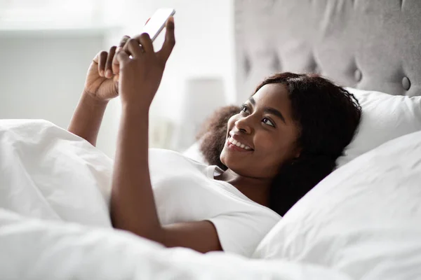 Alegre joven negro mujer charlando con el novio en la cama —  Fotos de Stock
