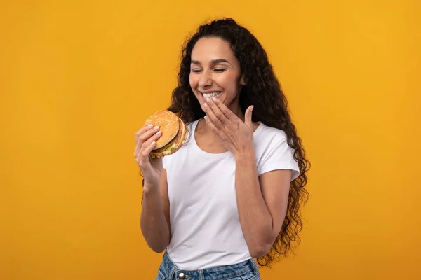 スタジオでバーガーを食べる幸せな笑いの女性 — ストック写真
