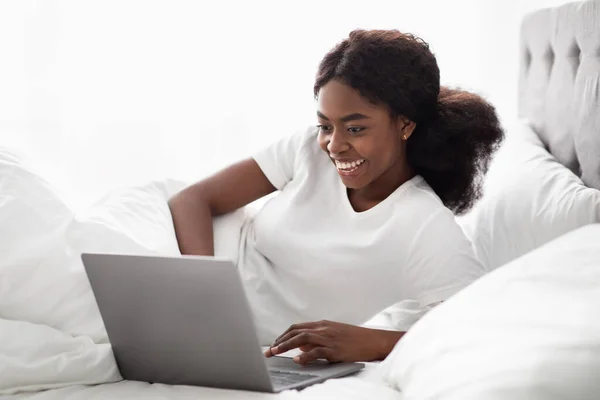 Allegro afroamericano signora navigare su Internet a letto — Foto Stock