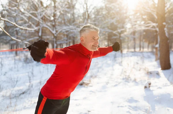 Deportes de invierno al aire libre. Feliz entrenamiento de hombre mayor con correas de fitness en el soleado parque nevado, espacio libre —  Fotos de Stock