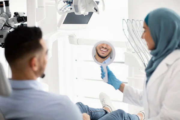 Arabischer männlicher Patient betrachtet sein Lächeln nach der Behandlung in einer Zahnklinik — Stockfoto