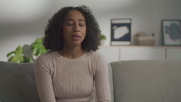 Erkältung und Grippe. Junge kranke Afroamerikanerin niest, fühlt sich zu Hause auf dem Sofa krank, Nahaufnahme Porträt, freier Raum — Stockvideo
