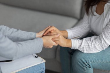 Profesyonel şefkat. Depresyondaki kadını destekleyen psikoterapist, elini tutan, klinikte oturan, kesilmiş