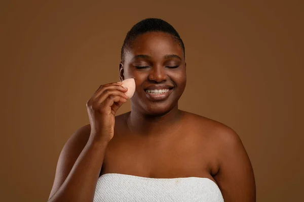 Mujer gordita negra con acné aplicando maquillaje con esponja —  Fotos de Stock