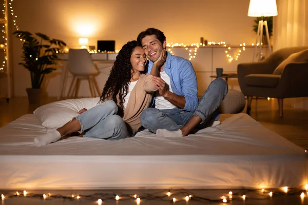 Casal feliz no amor abraçando sentado no colchão em casa — Fotografia de Stock