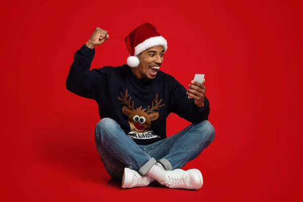 Happy zwarte man in Santa hoed met behulp van smartphone, gebaren — Stockfoto