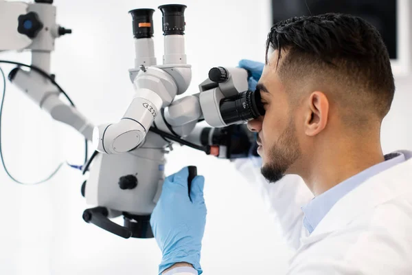 Tecnologías modernas para la salud. Médico árabe usando microscopio dental en clínica — Foto de Stock