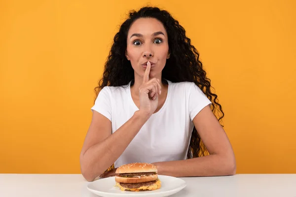 Hongerige dame toont stilte gebaar eten hamburger — Stockfoto