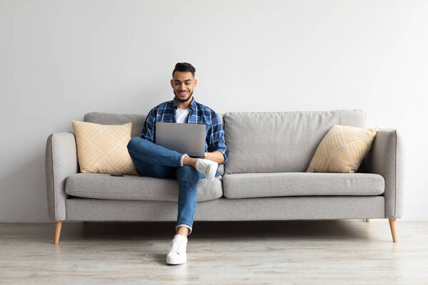 Portrait of smiling Arab man using laptop at home