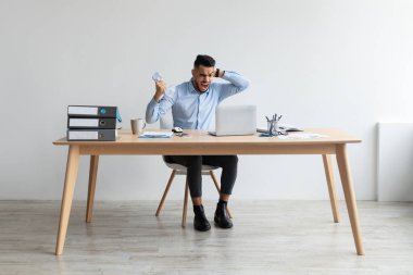 Kızgın Arap adam dizüstü bilgisayar kullanıyor, bağırıyor, ekrana bakıyor