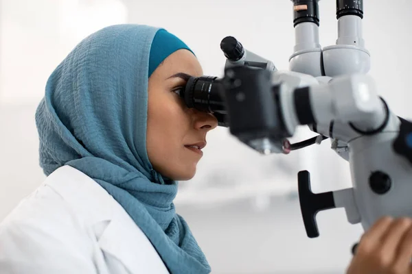 Moslim vrouwelijke medische werknemer in hidjab met behulp van tandheelkundige microscoop in de moderne kliniek — Stockfoto