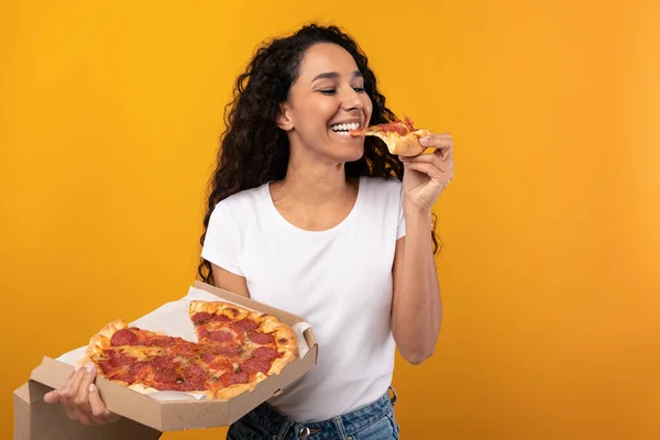 Happy Latin Woman Holding Box mordiendo pizza en el estudio — Foto de Stock