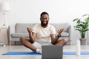 Beyaz tişörtlü, sakallı, neşeli, yakışıklı Afro-Amerikan adam koçla iletişim kuruyor.