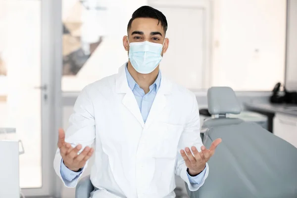 Usługi stomatologiczne. Portret arabskiego dentysty w masce medycznej rozmawiającego przed kamerą — Zdjęcie stockowe
