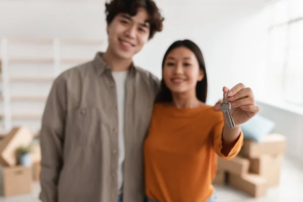Heureux couple asiatique montrant la clé de la maison à la caméra, déménageant dans leur propre appartement, foyer sélectif — Photo