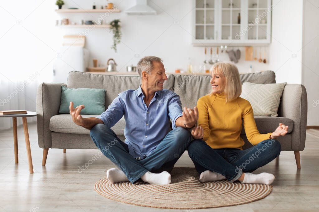 Mature Couple Doing Yoga Together Sitting In Lotus Position Indoor