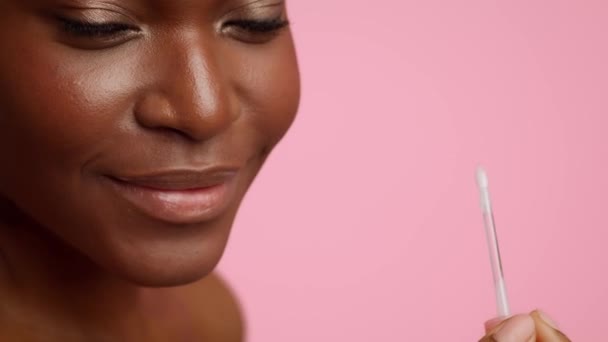 Unerkennbarer schwarzer weiblicher Lippenstift-Applikator über rosa Hintergrund, beschnitten — Stockvideo