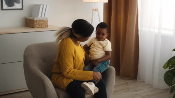 Aimer maman noire et son fils préscolaire se détendre dans la chaise à la maison — Video