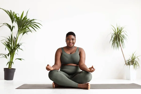 Atractiva mujer negra de talla grande haciendo ejercicio de yoga en el estudio —  Fotos de Stock