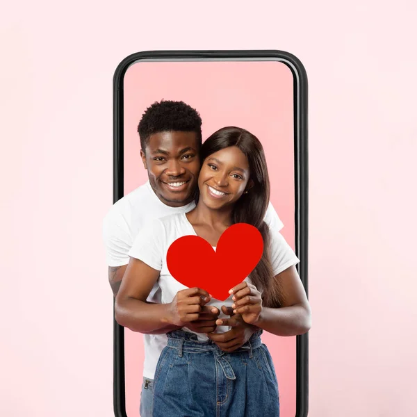 Joven pareja negra romántica abrazando, saliendo de la pantalla celular — Foto de Stock