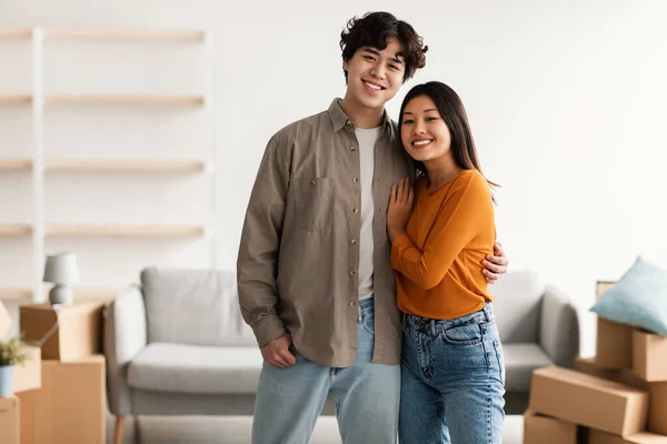 Concepto de reubicación del hogar. alegre joven asiático chico abrazando su encantadora esposa en su nuevo apartamento, espacio de copia —  Fotos de Stock