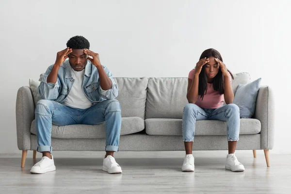 Deprimido jovem casal negro sentado no sofá e pensando — Fotografia de Stock