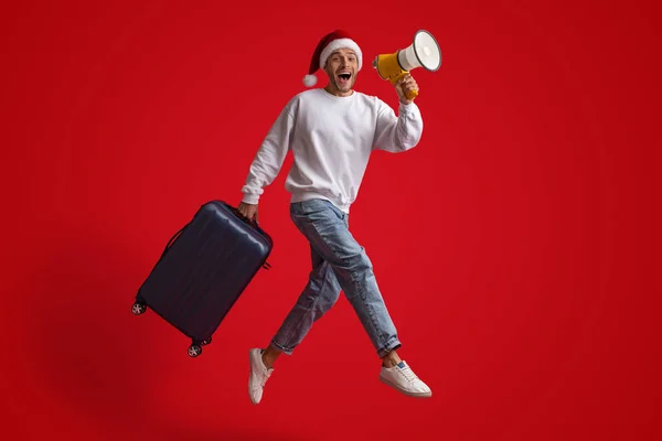 Człowiek w Santa Hat skacze z walizką i ogłasza z głośnik — Zdjęcie stockowe