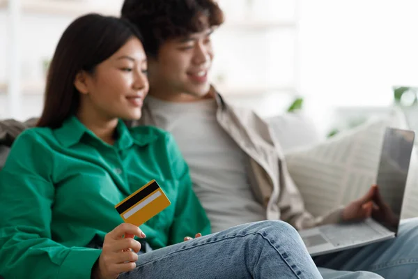 Millennial couple asiatique faisant des achats sur ordinateur portable, tenant la carte de crédit, effectuant le paiement à distance, en utilisant le service bancaire — Photo