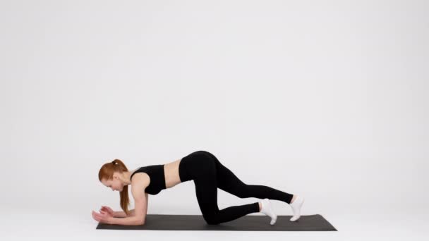 Тренировка на выносливость. Спортивная молодая женщина делает упражнения доски на коврике в студии — стоковое видео