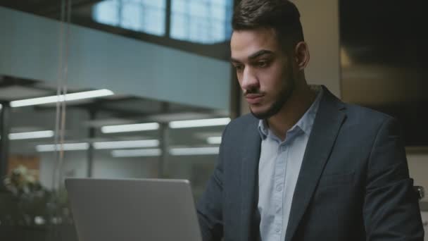 Proceso de trabajo. Joven gerente de Oriente Medio escribiendo en el ordenador portátil, haciendo plan en línea y el informe financiero en la oficina — Vídeo de stock
