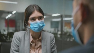 Yeni normal ve iş sahibi. Genç bir kadın, erkek iş arayanla konuşuyor, sorular soruyor, ikisi de koruyucu maskeler takıyor.