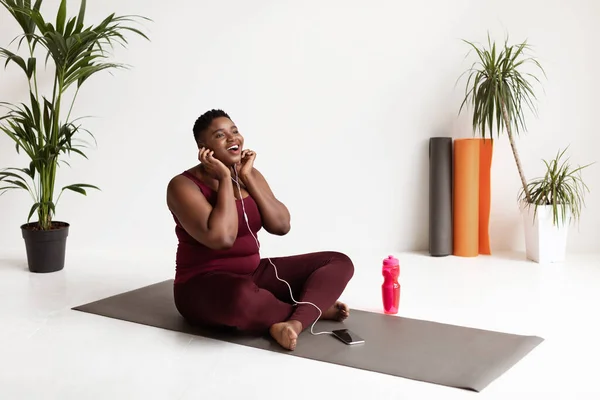 Extática mujer negra con sobrepeso disfrutando de la música mientras entrena —  Fotos de Stock