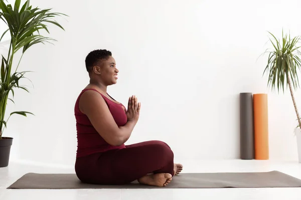 Vista lateral de la mujer negra gordita positiva que tiene práctica de yoga —  Fotos de Stock