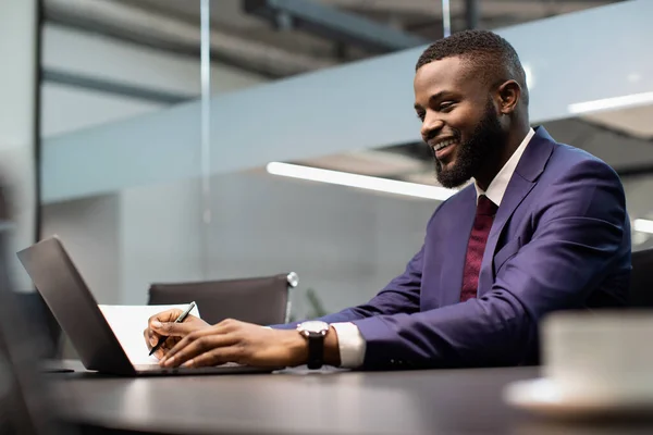 Joyeux entrepreneur afro-américain signant des papiers, travaillant sur un ordinateur portable — Photo