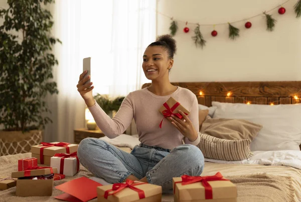 Internetowe przyjęcie świąteczne. Podekscytowana czarna dama korzystająca z telefonu komórkowego, robiąca selfie lub dzwoniąca wideo, świętująca Boże Narodzenie w domu — Zdjęcie stockowe