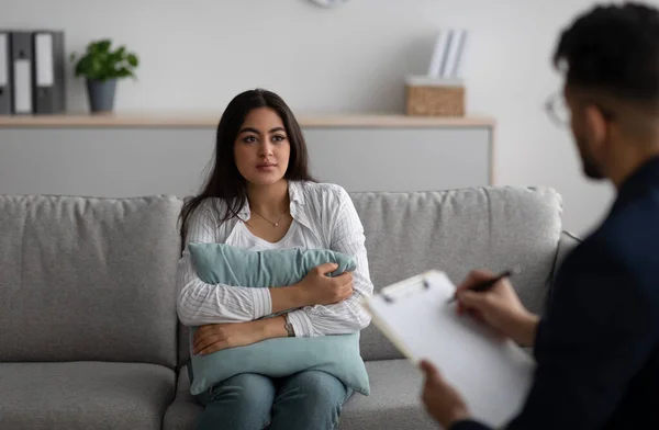 Psychotherapist consulting depressed arab lady, having therapy session, woman hugging pillow and talking to counselor — Stock Photo, Image