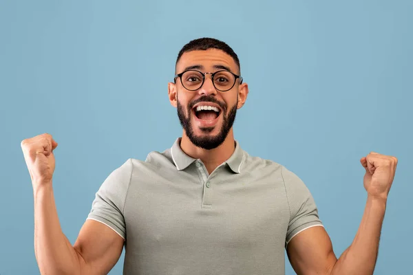 Satisfait homme arabe heureux se réjouissant du succès et criant dans l'excitation, debout sur fond bleu — Photo