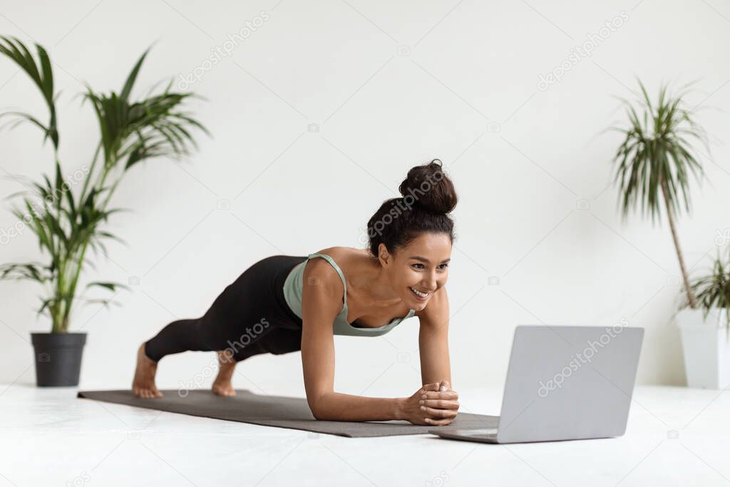 Domestic Trainings. Sporty Young Woman Doing Plank Exercise In Front Of Laptop