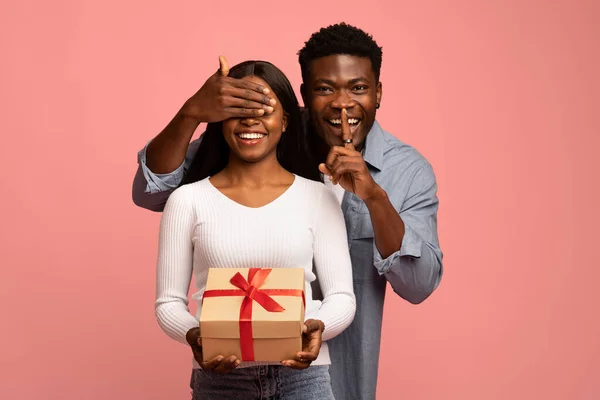 Couple millénaire noir avec boîte cadeau sur fond rose — Photo