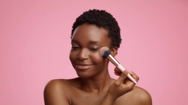 African Lady Applying Powder On Cheekbones Making Makeup, Pink Background — Stockvideo