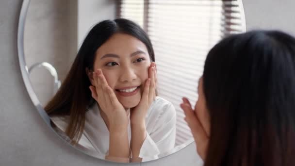 Pflegekonzept. Hübsch jung asiatisch weiblich looking at spiegel und touch face — Stockvideo