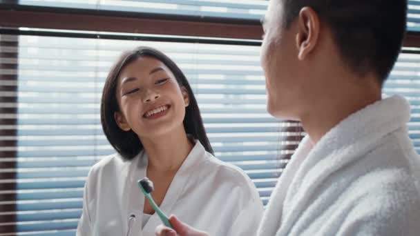 Ευτυχισμένο ασιατικό ζευγάρι βουρτσίζει τα δόντια με οδοντόβουρτσα στο μπάνιο — Αρχείο Βίντεο