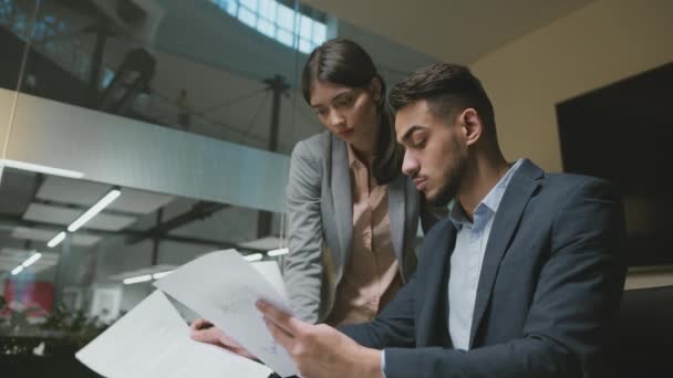 Período de prueba en el trabajo. Joven líder del equipo de hombres de Oriente Medio explicando los detalles del proyecto a la mujer recién llegada — Vídeos de Stock