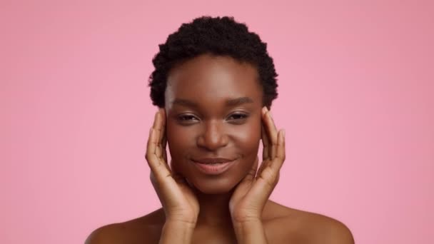 Entspannte Afroamerikanerin massiert Tempel vor rosa Hintergrund — Stockvideo