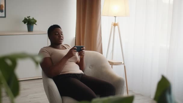 Overweight Black Female Playing Mobile Game On Smartphone At Home — Stockvideo