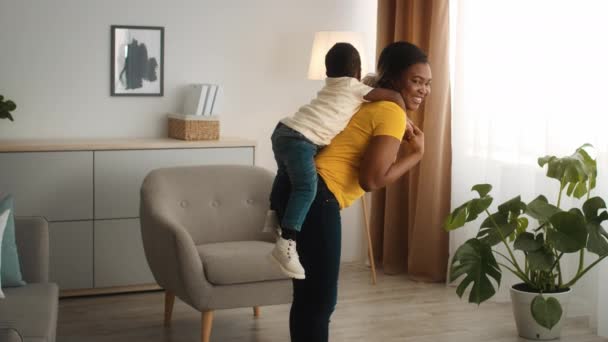 Cheerful Black Mom Making Squats At Home With Little Son On Back — Stock Video