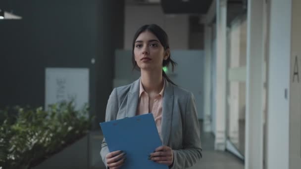 Портрет ділової жінки, яка ходить на зустрічі в офісному коридорі, несучи папку з бізнес-документами, слідує шотландському — стокове відео
